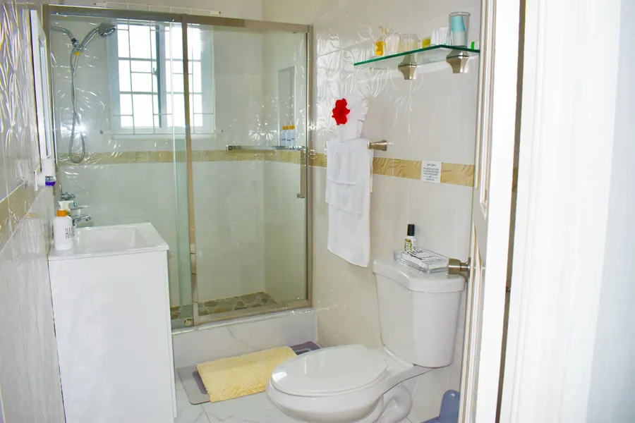 Glass walk-in shower in a white tiled bathroom